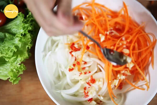 Tiến hành trộn đều nộm với đu đủ và cà rốt